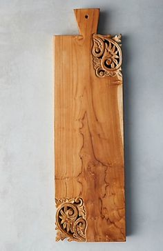 a wooden cutting board with an intricate design on the front and back side, hanging from a hook