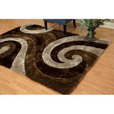 a brown area rug with white swirls on the top and bottom, in front of a wooden floor