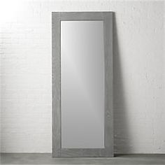 a mirror sitting on top of a wooden floor next to a white brick wall in an empty room