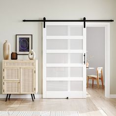 a room with a white door and wooden cabinet in it, next to a painting on the wall