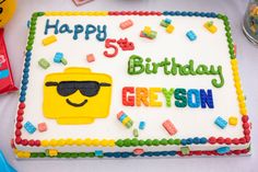 a birthday cake with the name greyson on it and legos in the background