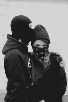 two people standing next to each other in front of a white wall with snow on it