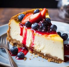 a piece of cheesecake on a plate with blueberries and strawberries in it