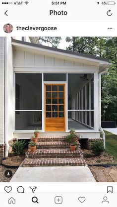 a small white house with an orange door and windows on the front porch, surrounded by brick steps