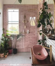 a bathroom with pink tiles and potted plants