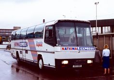 a bus parked in front of a building on a rainy day with people standing outside