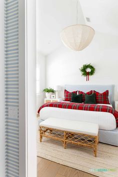 a white bedroom with red and green plaid bedding