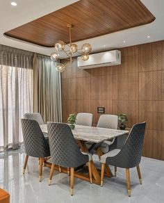 a dining room table with chairs and a chandelier hanging from the ceiling above it