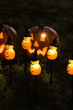 lighted pumpkins with faces on them in the grass