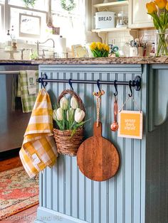 a kitchen with blue cabinets and wooden utensils hanging on the wall next to a potted plant