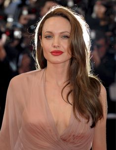 a woman with long brown hair wearing a pink dress and red lipstick on her lips