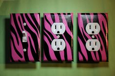 three pink and black zebra print outlet covers on a green wall with two white outlets