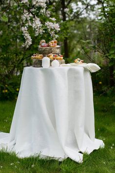 a table topped with pastries and flowers on top of a lush green grass covered field