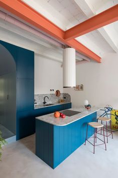 a kitchen with blue cabinets and counter tops next to an orange bar stool in the center