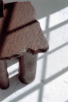 a wooden bench sitting on top of a white floor next to a window with blinds