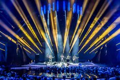 a large group of people sitting on top of a stage with lights in the background