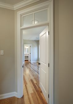 an empty room with hard wood flooring and white trim on the door, looking into another room