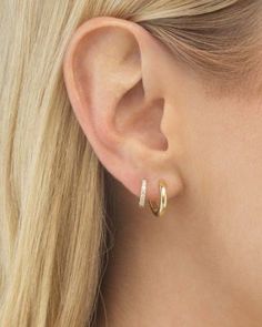 a close up of a person wearing gold earring with diamond hoops on their ears