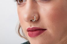 a woman wearing a nose ring with a crescent piercing on it's middle lip