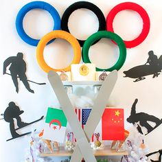 an olympic themed wall hanging on the side of a white wall with various sports related items