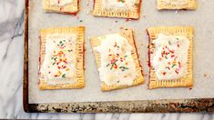 small pastries with sprinkles and white frosting on a baking sheet