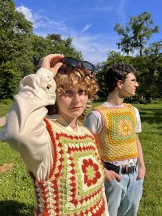 two young men standing next to each other in the grass with their hands on their head