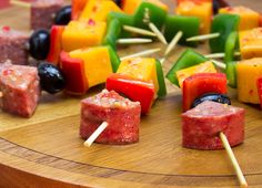 several skewers of different kinds of food on a wooden table with the words marinated summer sausage kabobs