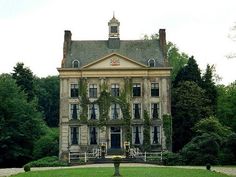 an old house with trees and bushes around it