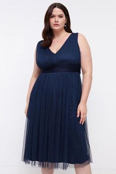 a woman in a blue dress poses for the camera with her hands on her hips