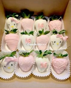 hello kitty chocolate covered strawberries are arranged in a cardboard box with green leaves and pink bows