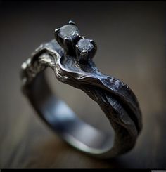 a silver ring with two stones on it's sides, sitting on top of a wooden