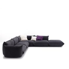 a large black couch sitting on top of a white floor next to a purple pillow