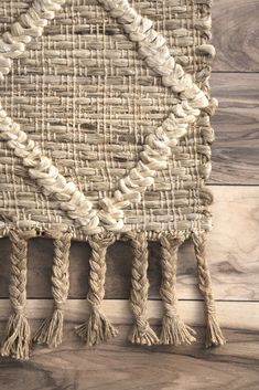 an area rug with tassels on top of it and wood flooring in the background