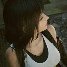 a woman with long black hair holding a cell phone to her ear and looking off into the distance