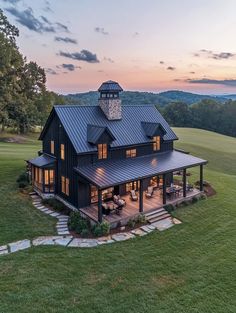 a large black house sitting on top of a lush green field