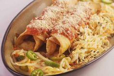 an enchilada dish on a plate with shredded cheese and green peppers