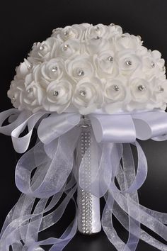 the bridal bouquet is adorned with white roses and crystal beadings, along with ribbon