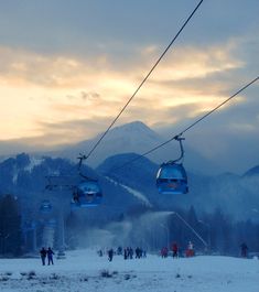 two ski lifts with people skiing down the hill in the background at sunset or dawn