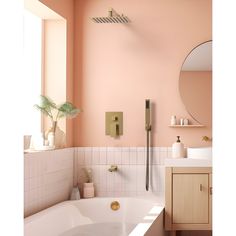 a bath tub sitting under a bathroom mirror next to a sink in a room with pink walls