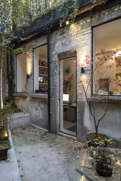 the outside of a building with lots of windows and plants in pots on the sidewalk