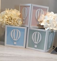 three small boxes with flowers in them sitting on a table next to a vase filled with white and blue flowers