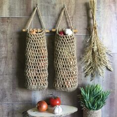 two crocheted bags hanging on the wall next to some vegetables and fruit in baskets