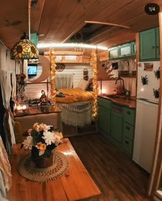 a kitchen with green cabinets and wooden flooring in the middle of it is lit up by string lights