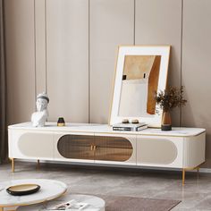 a living room with a white entertainment center and gold accents on the sideboard, in front of a beige wall