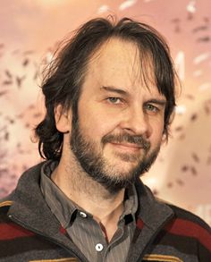 a close up of a person wearing a sweater and smiling at the camera with birds in the background