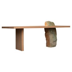 a long wooden table with a rock on it's end and a piece of wood sticking out of the top