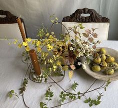 a table topped with plates and vases filled with flowers on top of a white table cloth