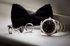 a bow tie, watch and cufflinks on a table