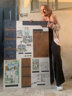 a woman standing next to a sign with plans on it and smiling at the camera