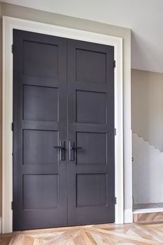 two black doors in a room with wood floors